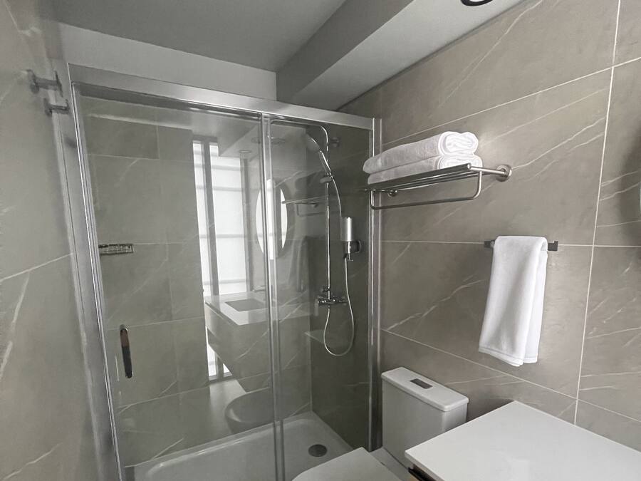 A modern bathroom with a glass-enclosed shower, a white toilet, and a vanity with a mirror.
