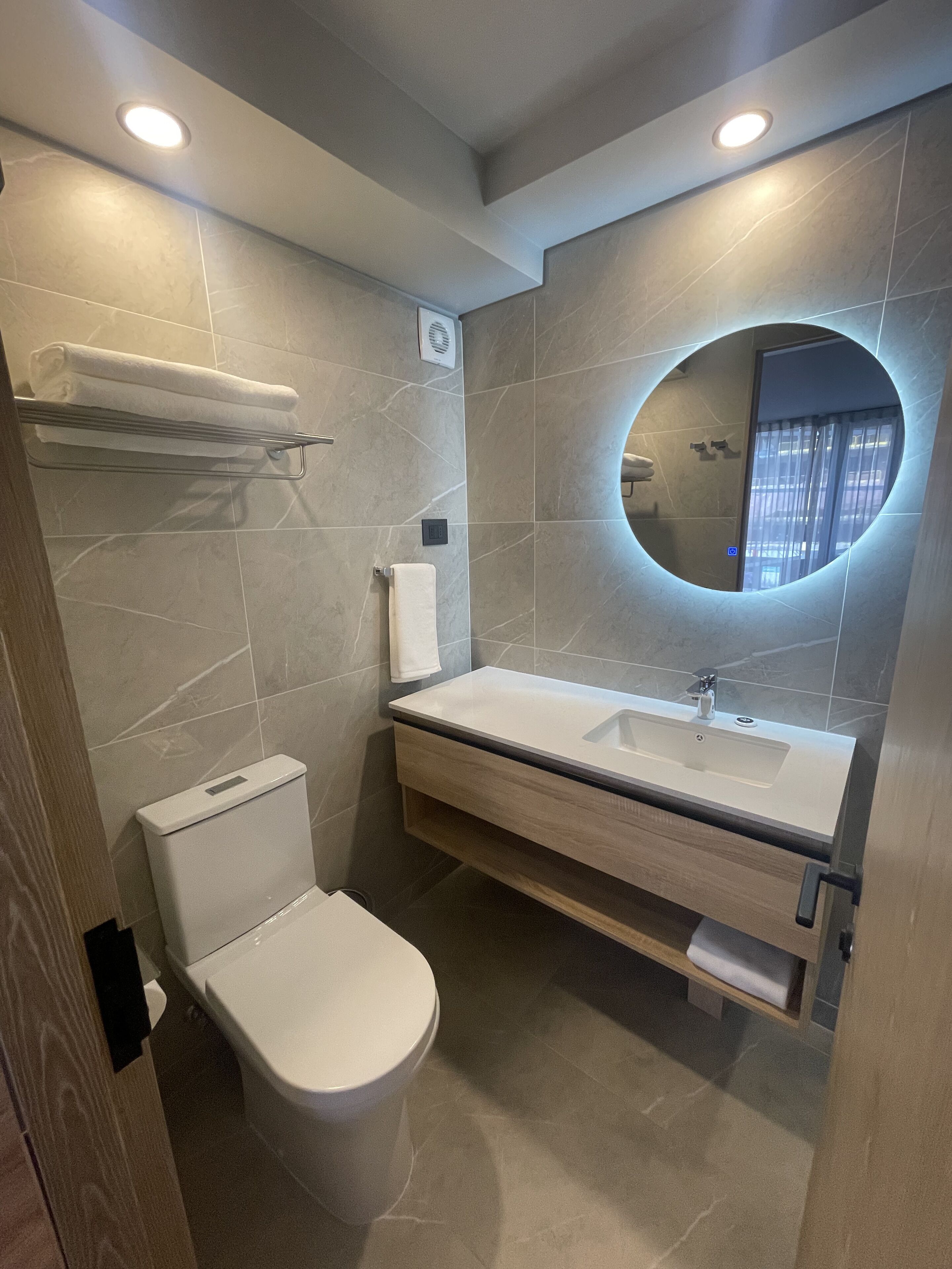 A modern bathroom with a toilet, sink, and mirror.
