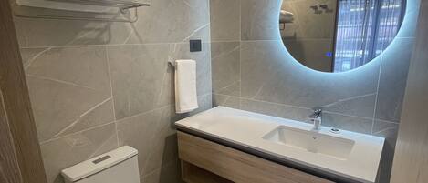 Ein modernes Badezimmer mit Toilette, Waschbecken und Spiegel.