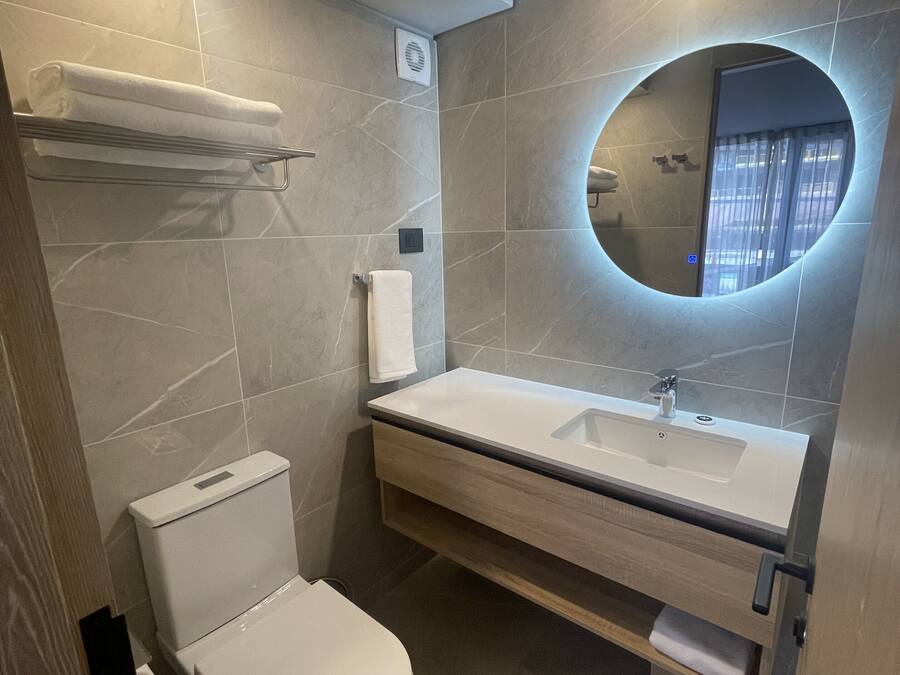 A modern bathroom with a toilet, sink, and mirror.