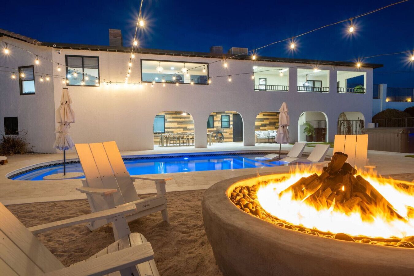 A modern house with a swimming pool, outdoor seating, and a fire pit.