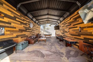 Un espacio interior con un diseño de pared de madera, un piano, un sofá de cuero y un comedor con mesas y sillas.