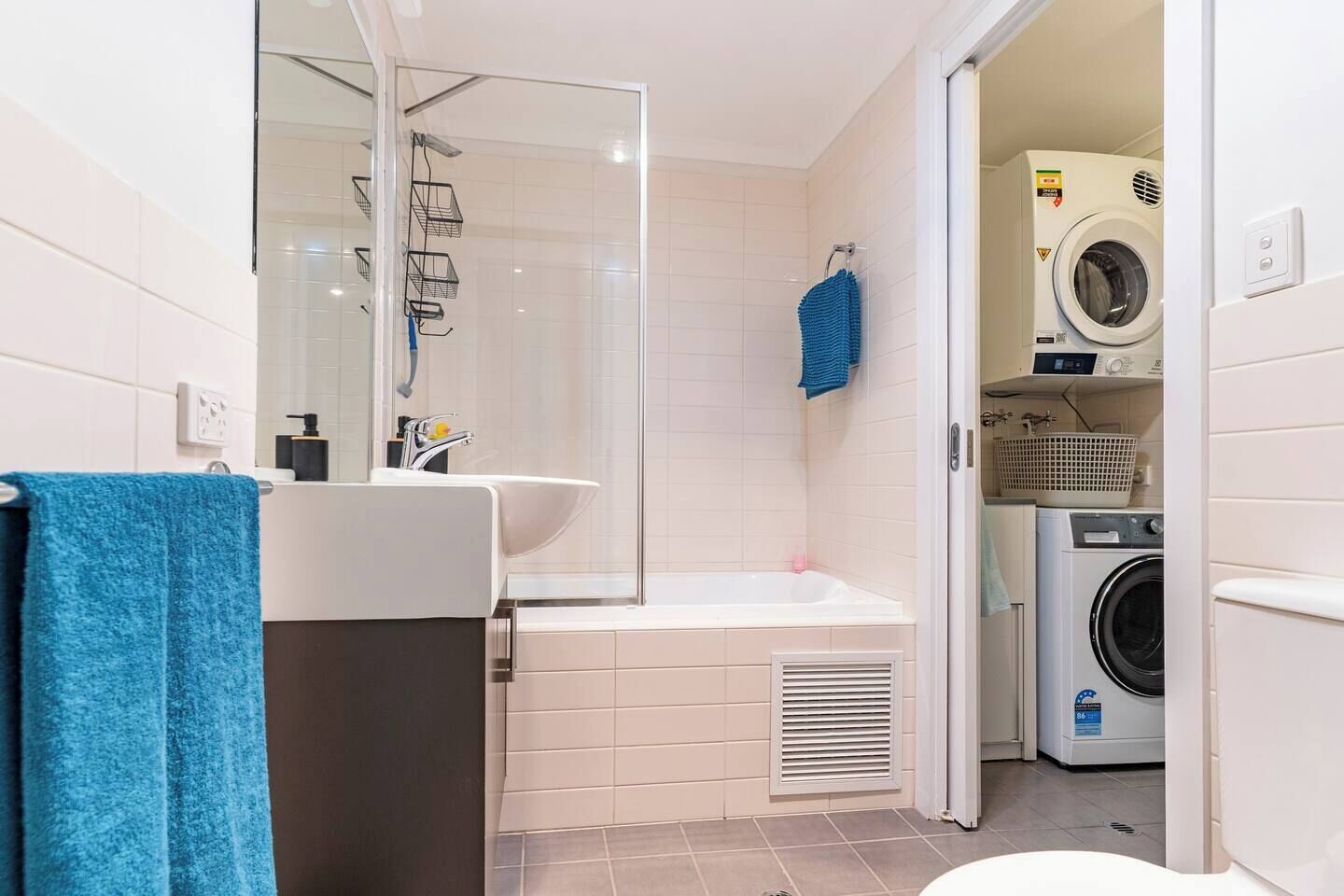 A bathroom with a bathtub, a sink, a mirror, a shower, and a washing machine.