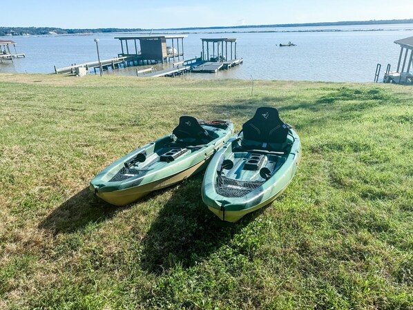 Two kayaks on a grassy area near a dock with a body of water in the background. - Fishing paradise!!! House on Livingston with private dock! (Trinity)