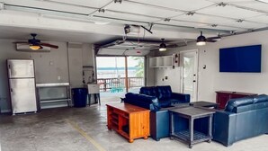 Una habitación tipo garaje con kitchenette, un sofá de cuero azul, una mesa de madera y un ventilador de techo.