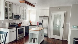 Una cocina moderna con armarios blancos, electrodomésticos de acero inoxidable y suelo de madera.