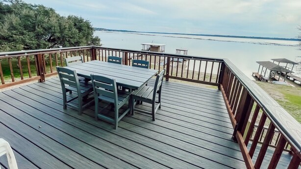 Una terraza de madera con una mesa y sillas, con vista a una masa de agua.