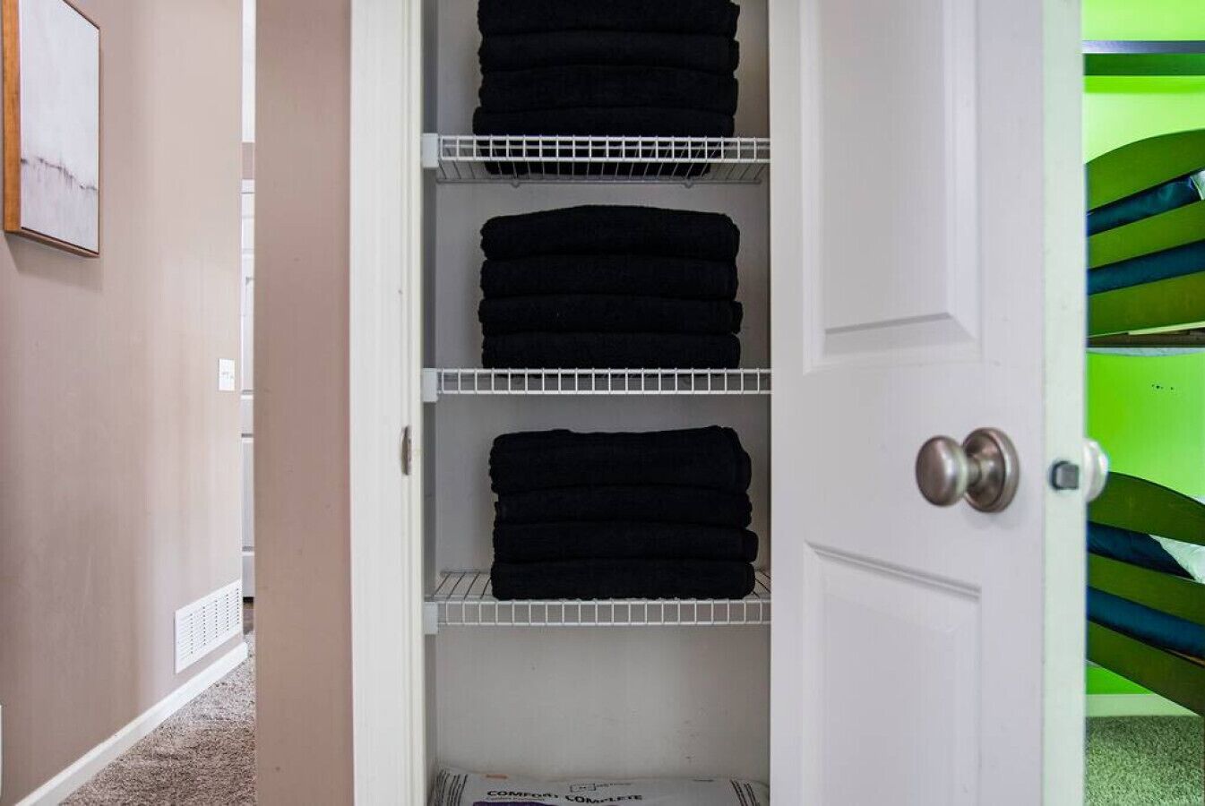 A closet with three shelves holding folded towels.