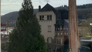 En byggnad med en fasad av sten, ett torn och ett stort träd framför.