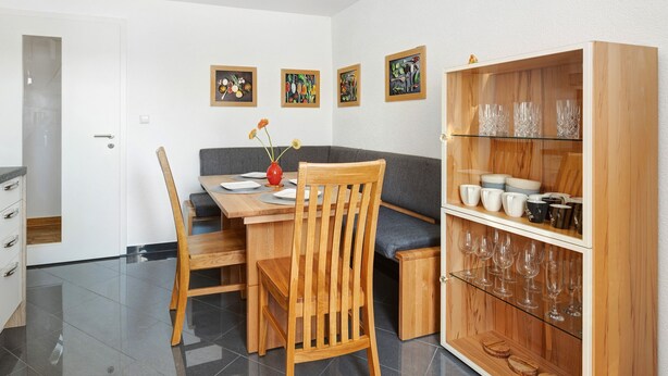 Ein Essbereich mit einem Holztisch, Stühlen, einer Bank und einem Schrank mit Glastüren.