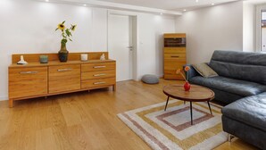 Ein modernes Wohnzimmer mit einem Holzkabinett, einer Couch, einem Couchtisch und einer Vase mit Blumen.