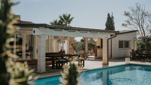 Un espace aménagé au bord de la piscine, avec une pergola, du mobilier d’extérieur et une vue sur la piscine.