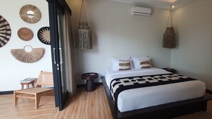 A modern bedroom with a bed, bedside tables, a wooden chair, and decorative wall hangings.