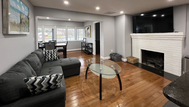 A living room with a sofa, a glass coffee table, a fireplace, and a dining area in the background.