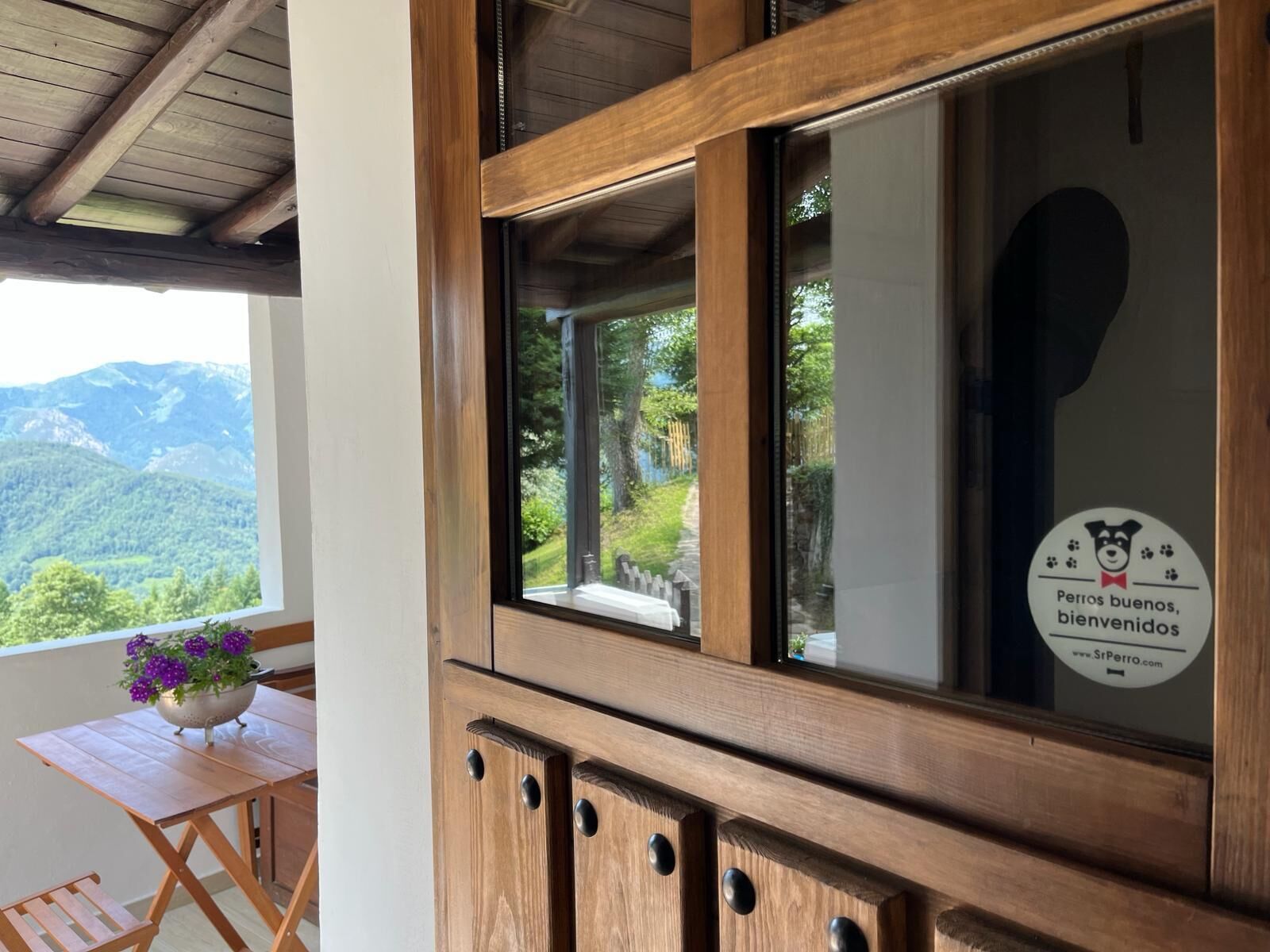 A wooden-framed window with a view of a mountainous landscape.