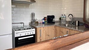 A kitchen with white subway tiles, a stainless steel range hood, a gas stove, a coffee maker, and a sink with a modern faucet. - Casa Rural Independiente en Asturias, Admitimos Mascotas (Llanuces)