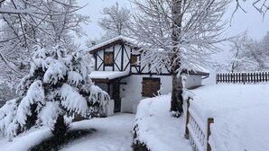 A snow-covered house with a traditional half-timbered facade, a wooden door, and a snow-covered lawn. - Casa Rural Independiente en Asturias, Admitimos Mascotas (Llanuces)