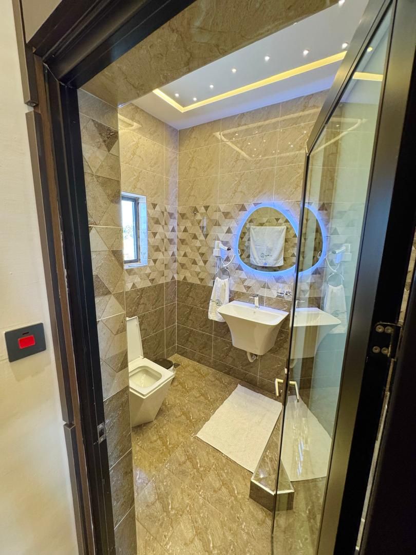 Un baño moderno con cabina de ducha de vidrio, inodoro, lavamanos y tocador.