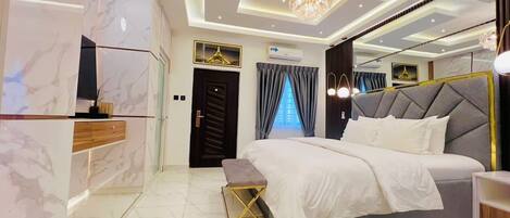 A modern bedroom with a large bed, a vanity with a mirror, and a chandelier.