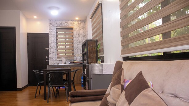 Un salon moderne comprenant un canapé, des fauteuils, une table à manger et un coin cuisine.