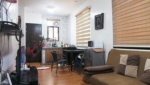 Un espace de vie compact comprenant un coin cuisine, un coin repas et un espace détente avec un canapé et des fauteuils.