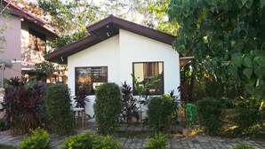 Une maison moderne à l’extérieur blanc et au toit brun, entourée d’un jardin bien entretenu et bordée d’un chemin pavé.