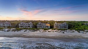 A beachfront property with multiple houses, a sandy beach, and a view of the ocean.