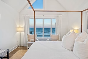 Un dormitorio con una cama grande, vistas al mar, un tragaluz y una lámpara de noche.