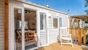 Una casa mobile con veranda, un'area pranzo con tavolo e sedie e una porta scorrevole in vetro.