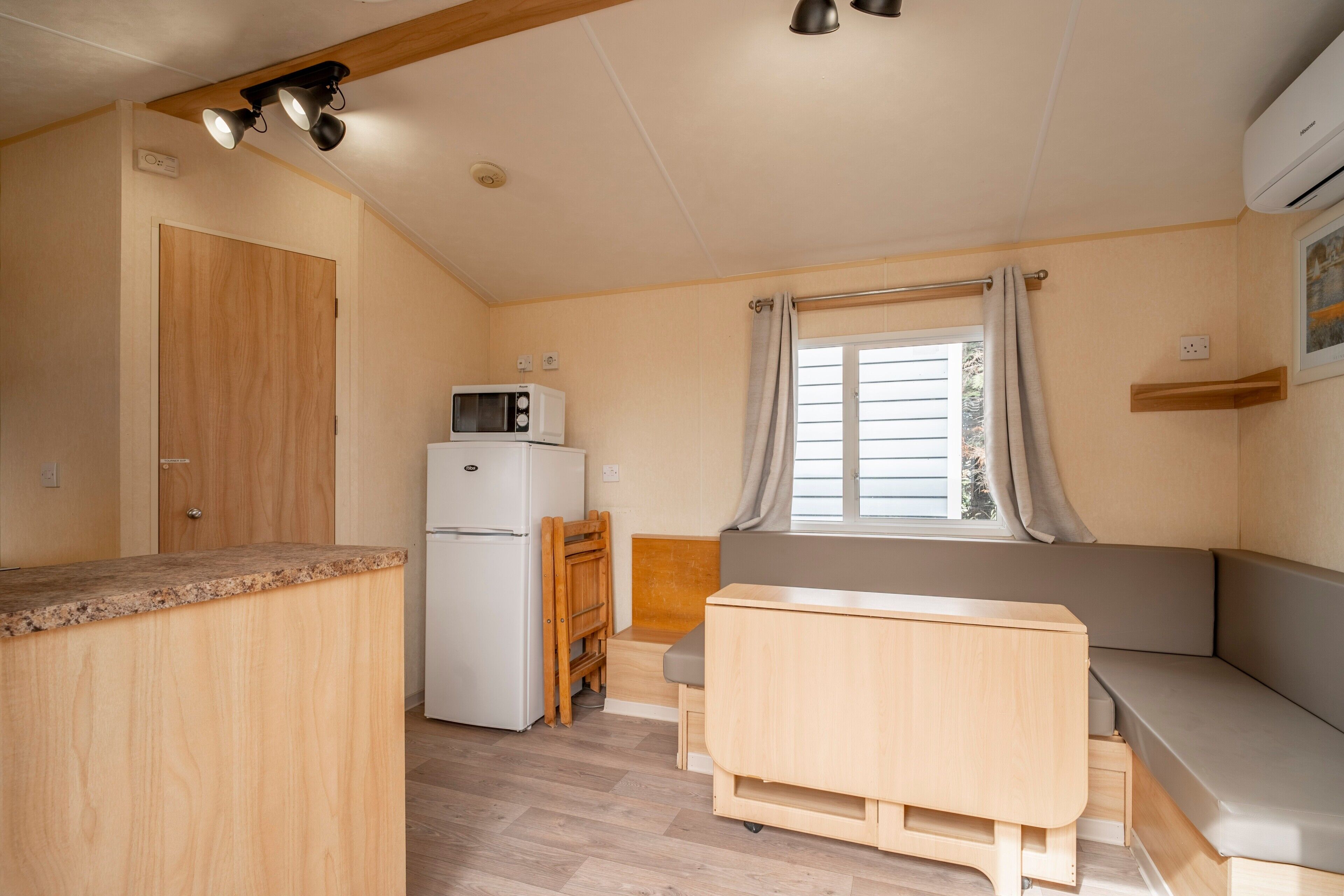 A compact kitchenette with a microwave, refrigerator, and wooden counter.
