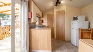Una cucina compatta con isola in legno, un forno a microonde e un frigorifero.