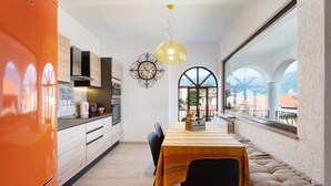 A modern kitchen with a dining area, large windows, and a view of the cityscape. - Mansarda Vialba Apartment in Holiday Home with Lake View and Balconies (Germignaga)