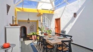 A dining area with a table set for four, a staircase, and a view through a skylight. - Holiday Villa 'Casa Jenabe' with Mountain Views, Private Terrace and Wi-Fi (la vegueta)