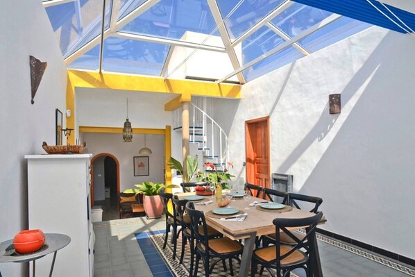 A dining area with a table set for four, a staircase, and a view through a skylight.