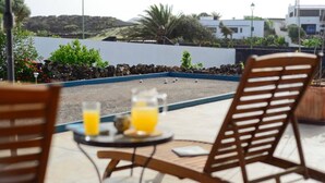 A patio with two wooden chairs, a small round table, and two glasses of orange juice. - Holiday Villa 'Casa Jenabe' with Mountain Views, Private Terrace and Wi-Fi (la vegueta)