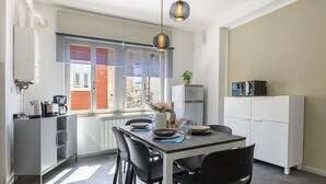 A modern kitchen with a dining area, featuring a window with a view, a refrigerator, and a coffee maker.