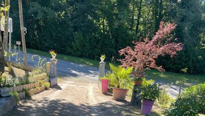 A gravel driveway leading to a gated entrance with potted plants and a wooden fence.