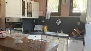 A kitchen with a brick island, double oven, and a window with curtains.