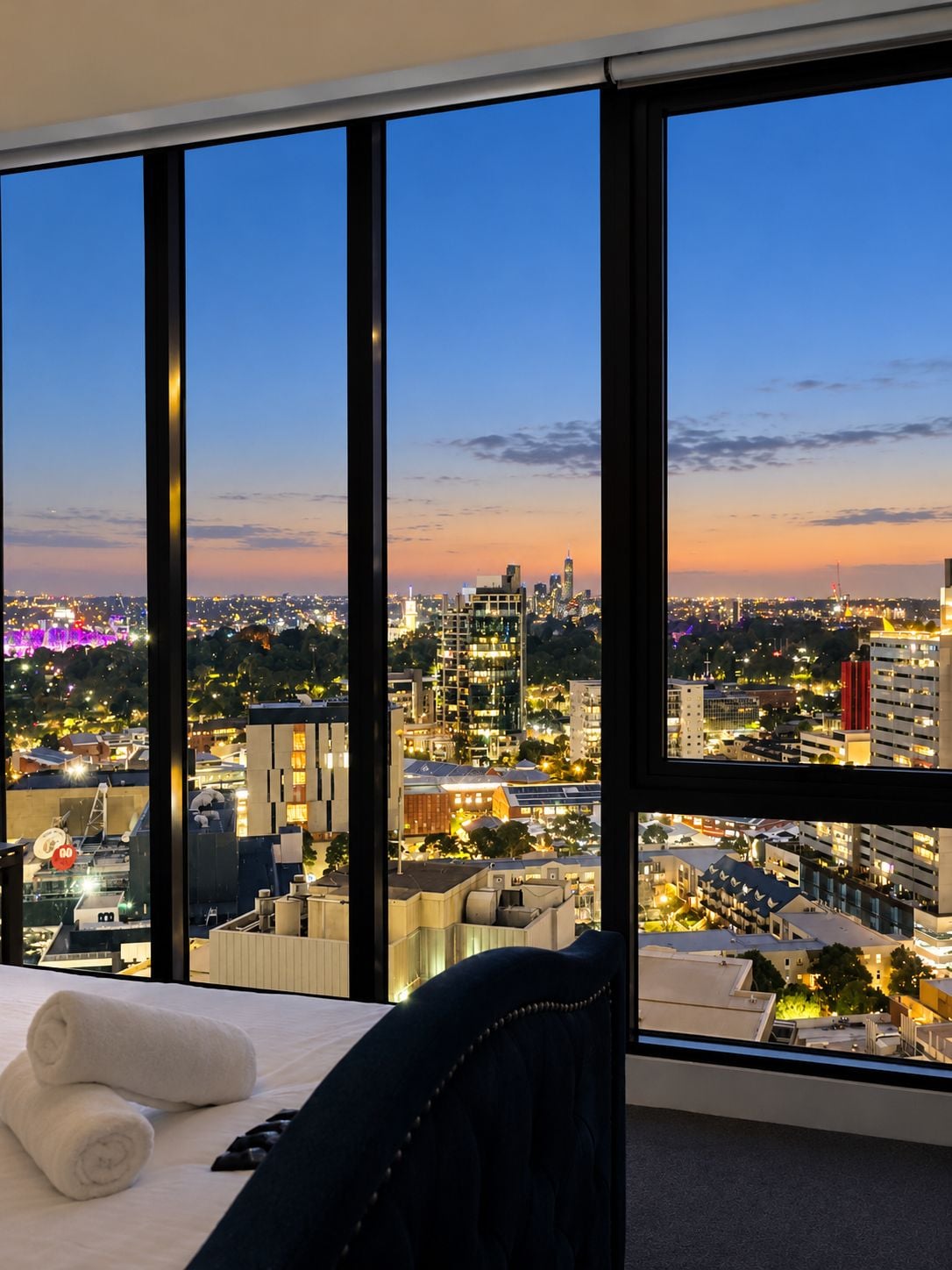 A hotel room with a large window offering a cityscape view.