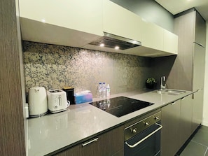 Een moderne keuken met een ingebouwde kookplaat, een spoelbak en een magnetron.