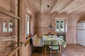 A rustic kitchen with a checkered tablecloth, wooden bench, and a refrigerator.
