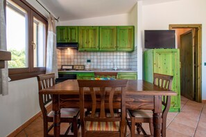 Une cuisine avec des meubles de rangement verts, une table à manger en bois et des chaises.