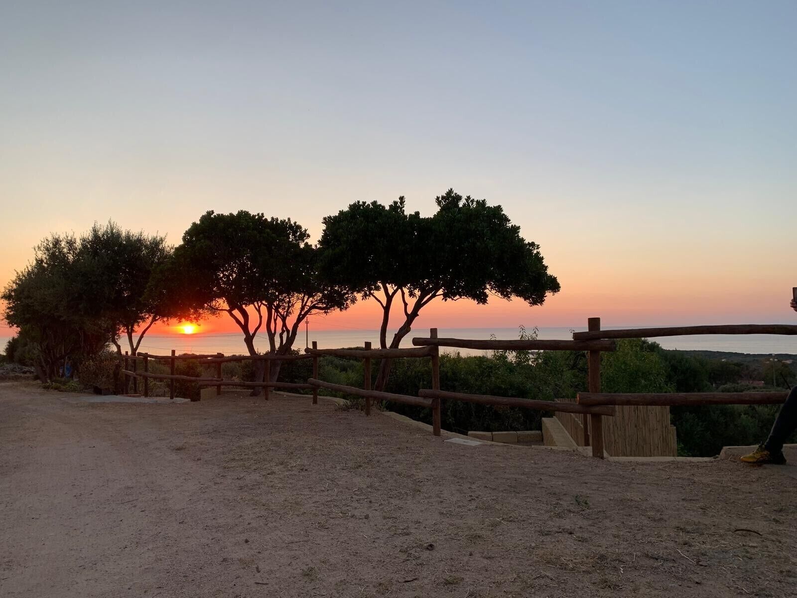 Ein Sonnenuntergang mit Holzzaun und Bäumen.