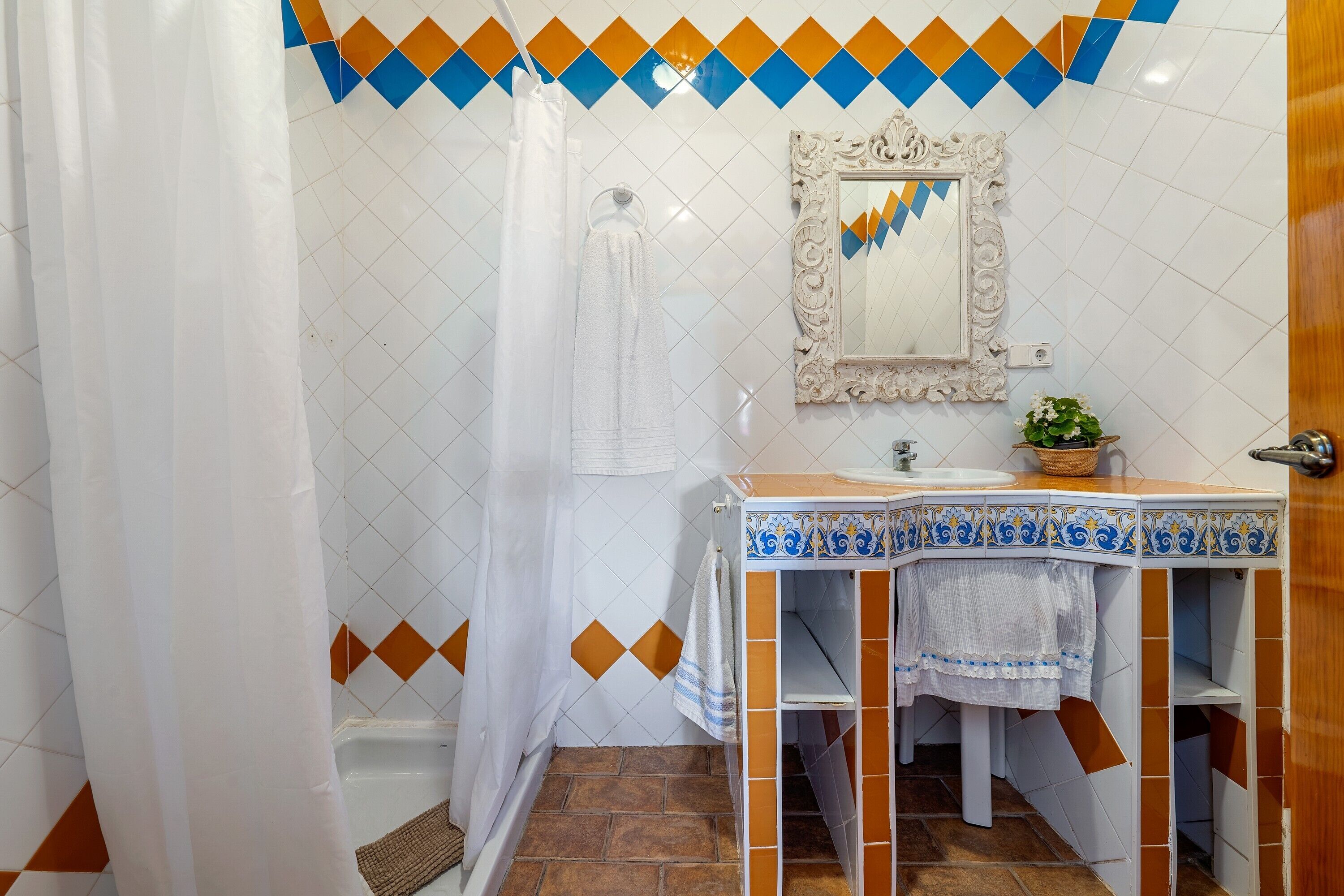 Un baño con ducha, lavamanos y espejo.