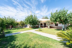 A residential property with a paved driveway, a small lawn, and a house with a tiled roof.