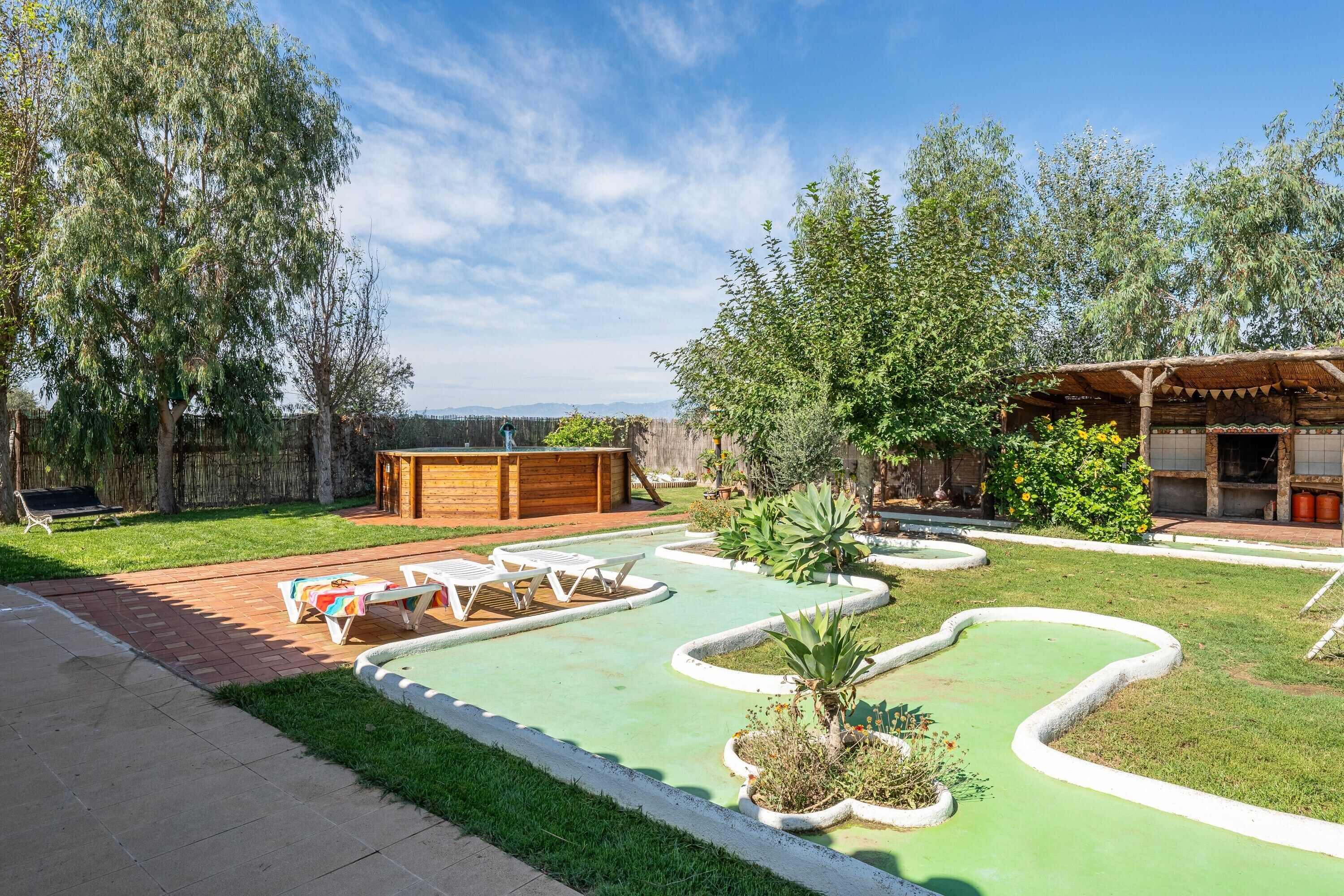 A backyard with a pool, lounge chairs, and a wooden pergola.