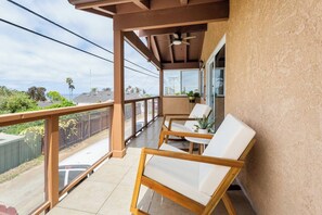 Enjoy the view from this balcony with a bathtub, two comfortable chairs, and a small table.