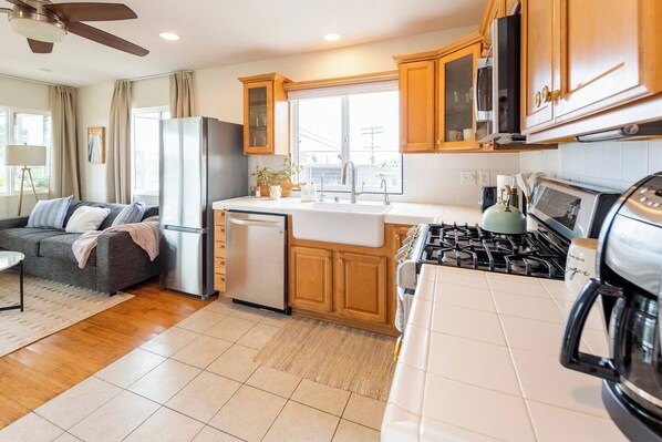 Enjoy cooking in the kitchen with a gas stove, dishwasher, and stainless steel refrigerator, adjacent to a cozy living area with a sofa and small table.