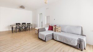 A modern living room with a grey sectional sofa, a dining table with chairs, and a hanging light fixture. - Holiday Home 'Parraga' with Mountain View, Private Terrace and Balcony (Cehejín)