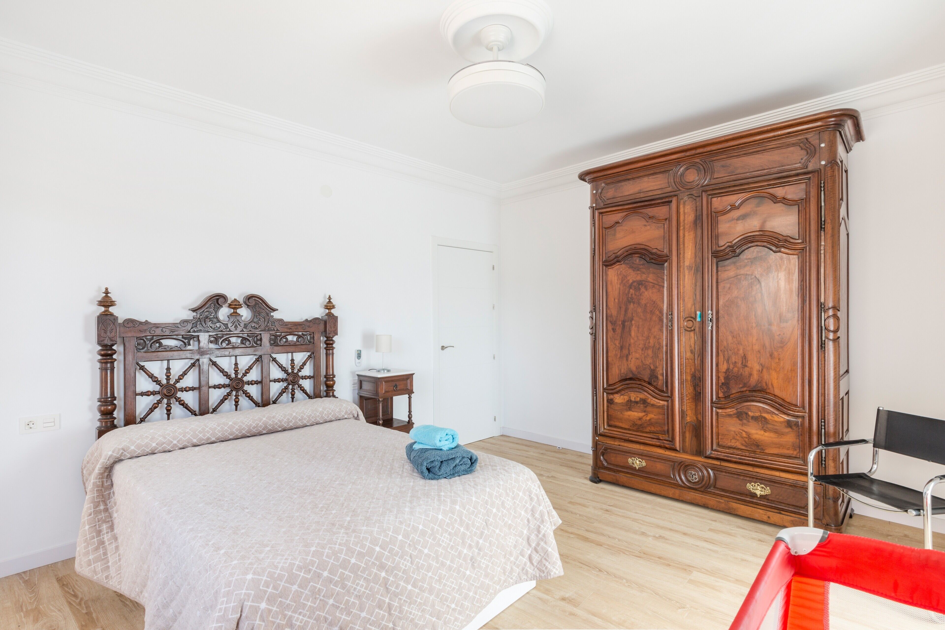 Un dormitorio con cama de madera, un armario, una silla y una mesita de noche.